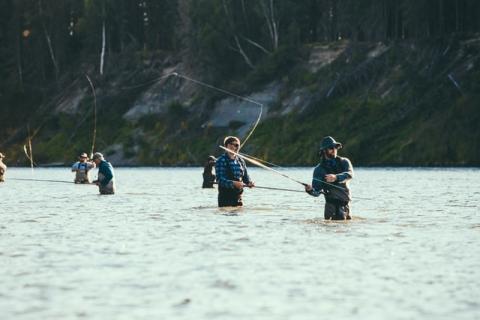 people standing in river with fishing poles