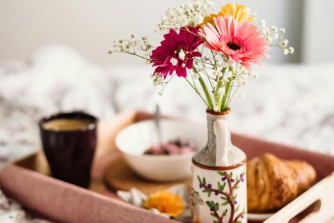 tray of breakfast items and flowers on a bed