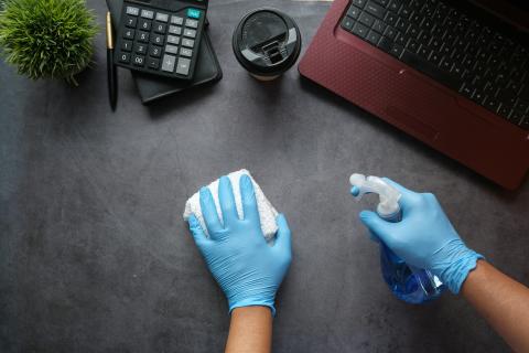 gloved hands cleaning a desk