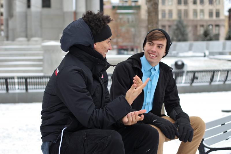 Two men talking outside on a bench