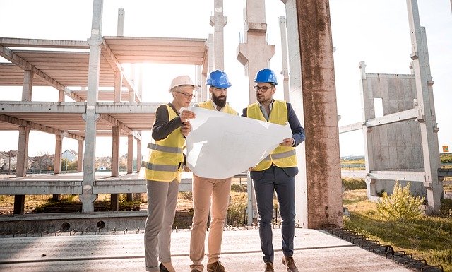 three architects reviewing draft on construction site