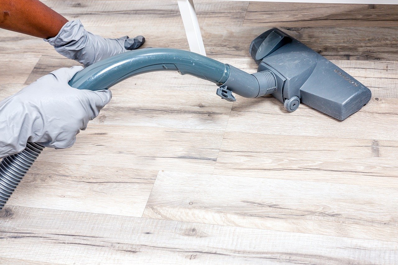 hands wearing gloves vacuuming hardwood floor